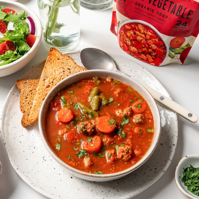 True Primal Beef and Vegetable Soup in bowl with toast and salad