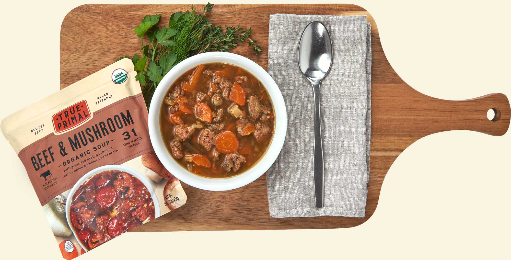 True Primal Beef and Mushroom Organic Soup on cutting board with spoon