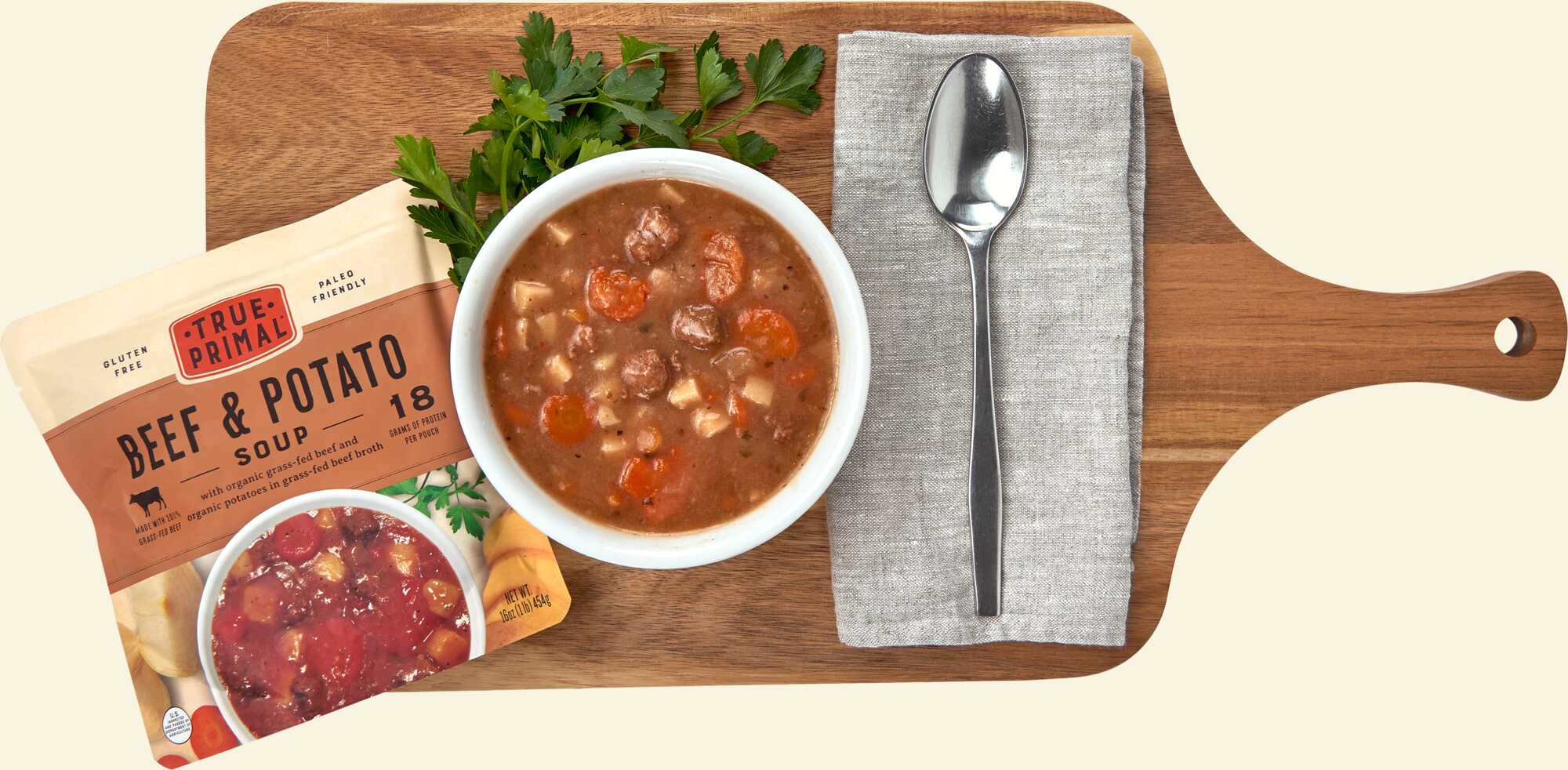 True Primal Beef & Potato Soup on cutting board with spoon
