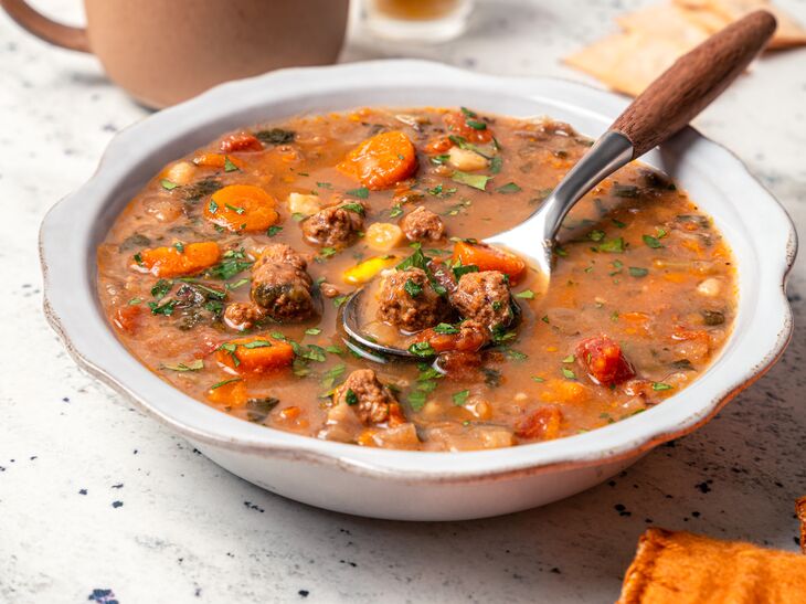 bowl of True Primal Hearty Beef Organic Soup next to tea and candle