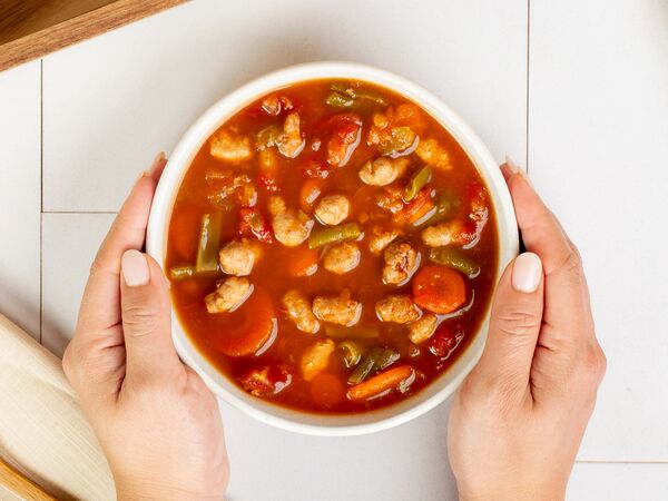 hands holding bowl of True Primal Chicken & Vegetable Soup