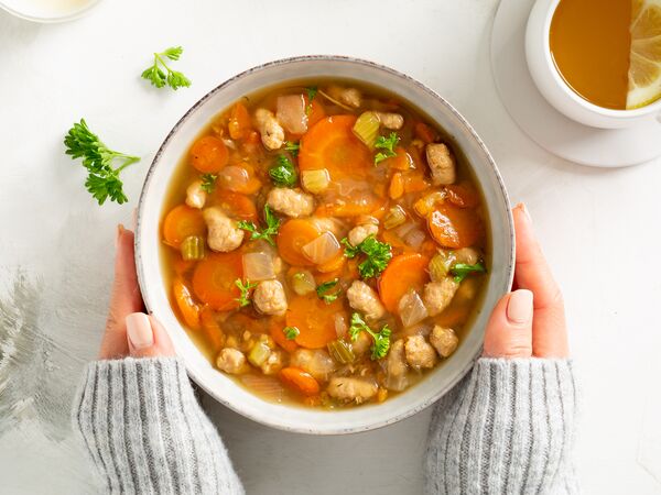 hands holding bowl of True Primal Roasted Chicken Soup
