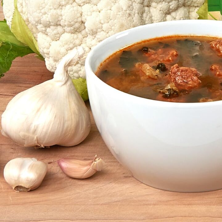 soup in bowl next to garlic and cauliflower