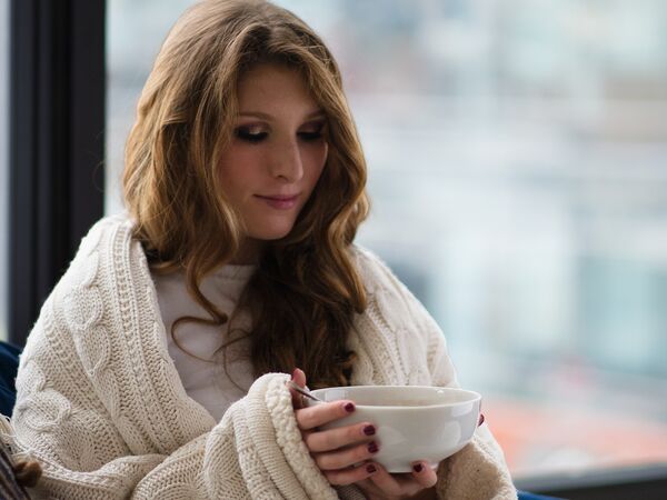 woman eating soup, wrapped in a blanket