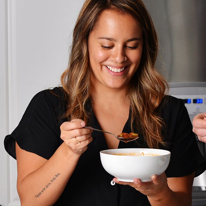 woman holding bowl of soup and smiling