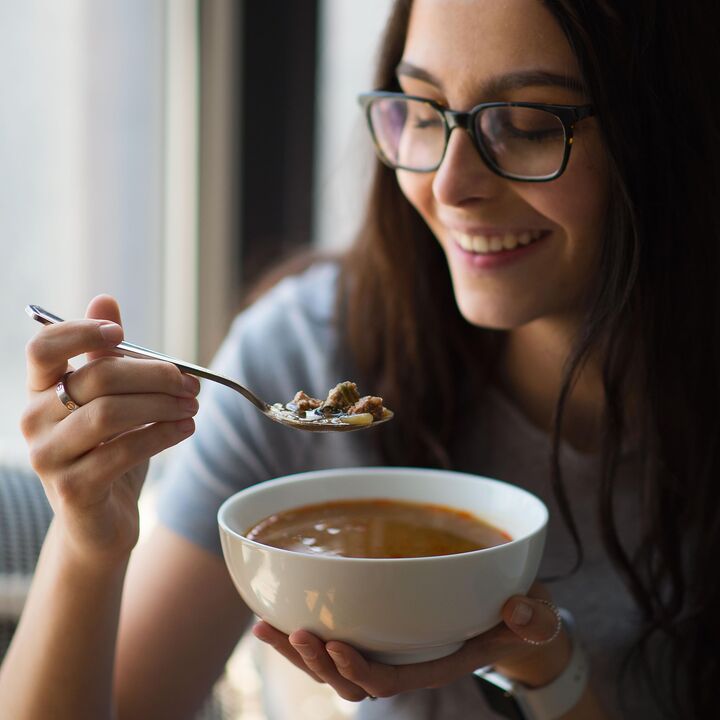 woman smiling with bowl of soup