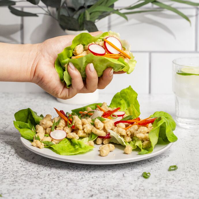 Hand holding lettuce cup filled with True Primal Pastured Chicken Mini Meatballs