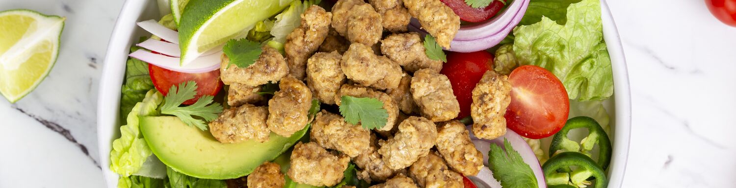 True Primal Grass fed Beef Mini Meatballs in a salad bowl next to a lime