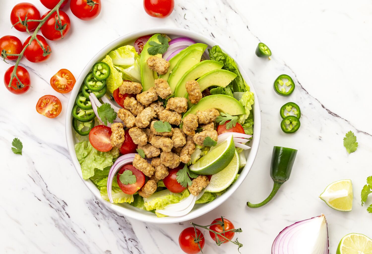 True Primal Grass fed Beef Mini Meatballs in a salad bowl with ingredients nearby
