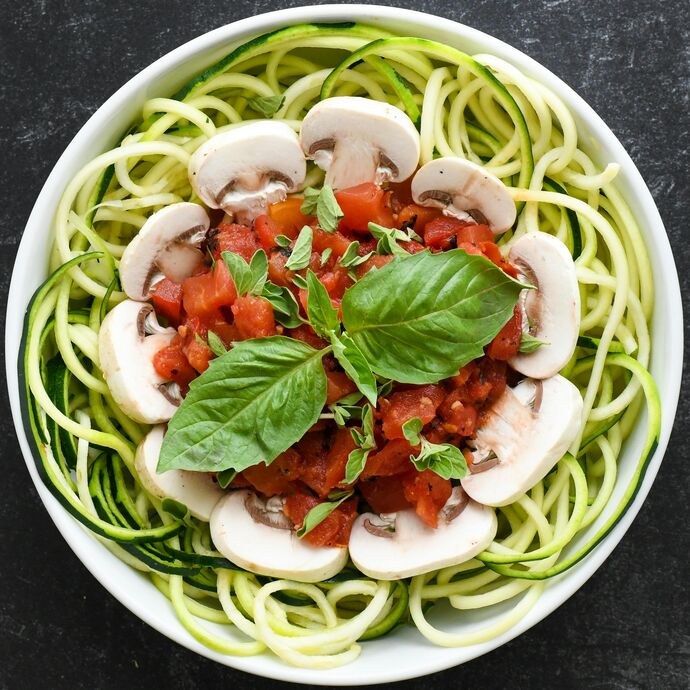 zoodles in bowl with mushrooms and tomatoes