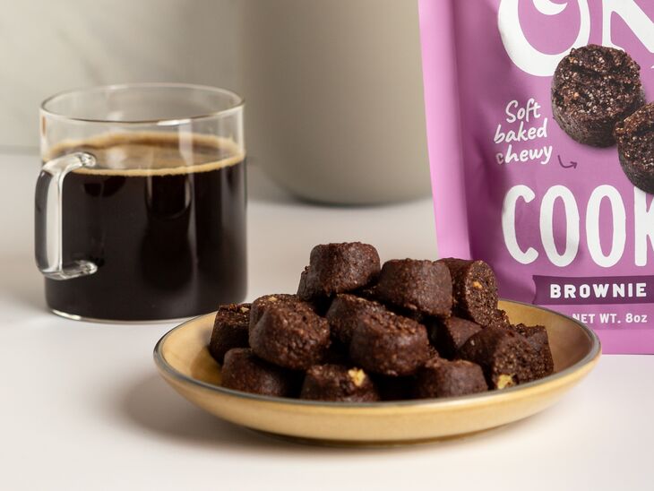 Ona Brownie Style Cookies on a plate and in a pouch next to a cup of coffee