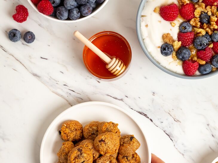 Ona Cinnamon Raisin Cookies on a plate next to a bowl of cereal, bowl of berries, and honey