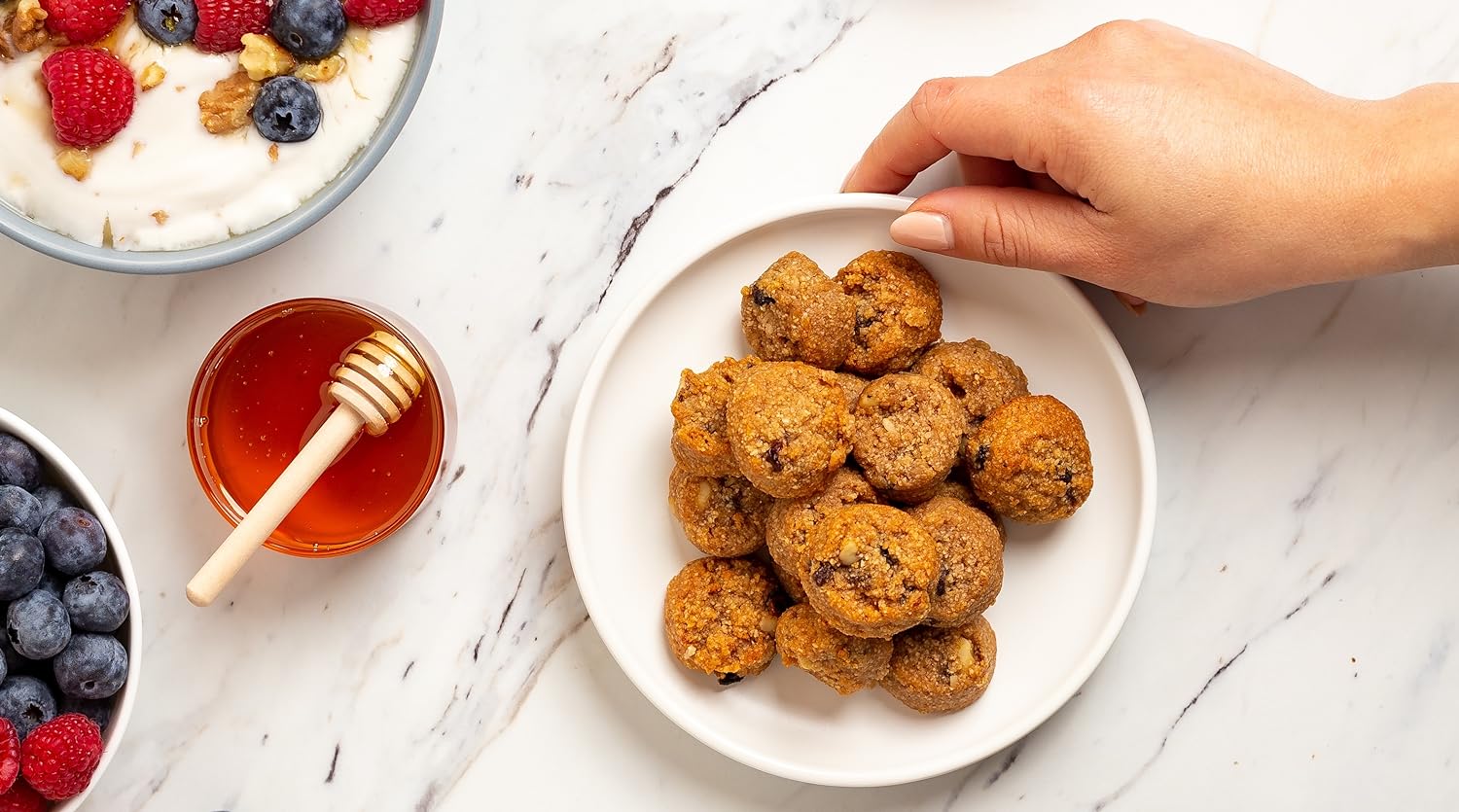 holding a plate Ona cookies next to bowls of honey and berries