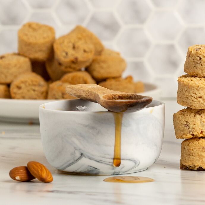 maple syrup dripping from a spoon next to Ona cookies