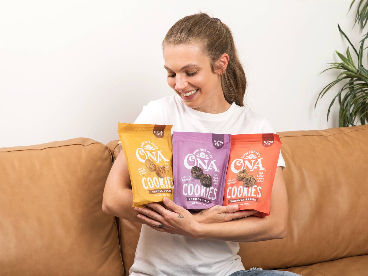 woman holding pouches of all three flavors of Ona cookies