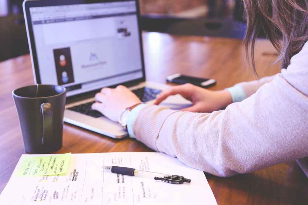 person working at desk with a laptop computer and papers