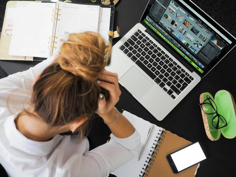woman holding her head while working at a computer