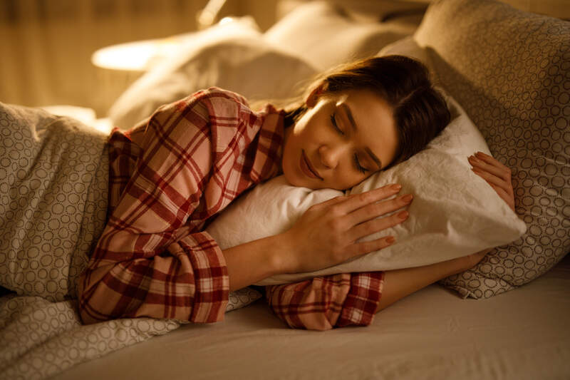 woman sleeping in bed hugging soft white pillow